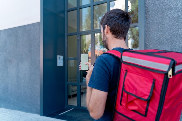 Delivery man with smartphone delivering parcel box . Technology and courier service concept. Horizontal view of rider delivering home a package.