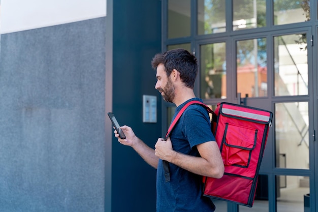 Delivery man with smartphone delivering parcel box . Technology and courier service concept. Horizontal view of rider delivering home a package.