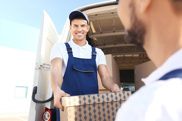 Delivery men unloading moving boxes from car