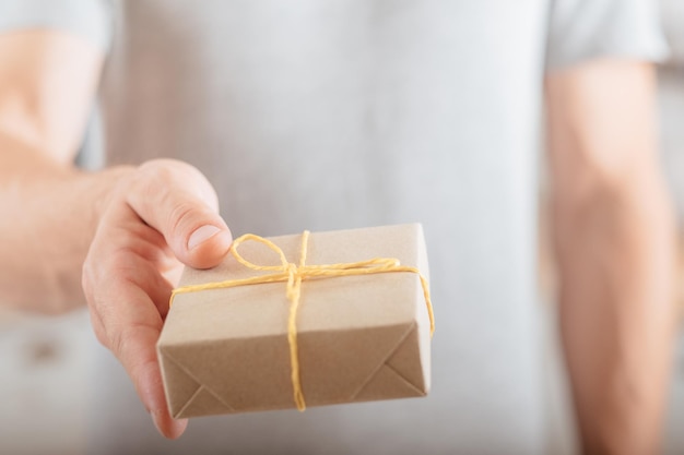 Delivery service Cropped shot of man giving rustic style package tied with yellow cord