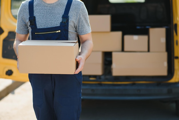 Delivery service employee Portrait of man working in delivery service Portrait of courier with box Courier next to minivan Delivery service career