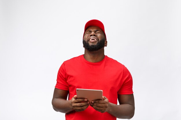 Delivery service - Portrait of Serious African American delivery man with tablet in silly aggressive expression and unhappy.  