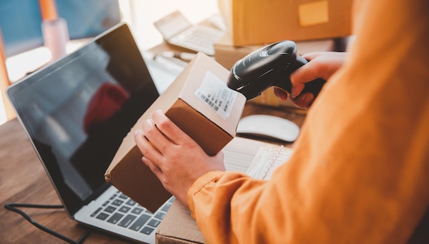 Delivery staff scanning cardboard box with barcode scanner to check products for customers