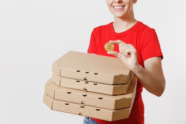 Delivery woman in red cap, t-shirt giving food order italian pizza in cardboard flatbox boxes isolated on white background. Female pizzaman working as courier holding bitcoin, coin of golden color.