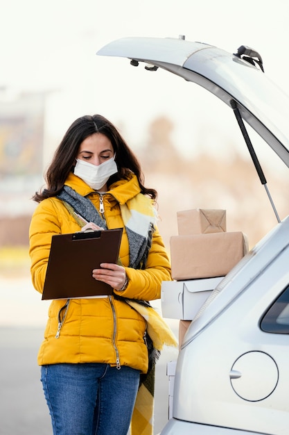 Delivery woman with mask carrying package