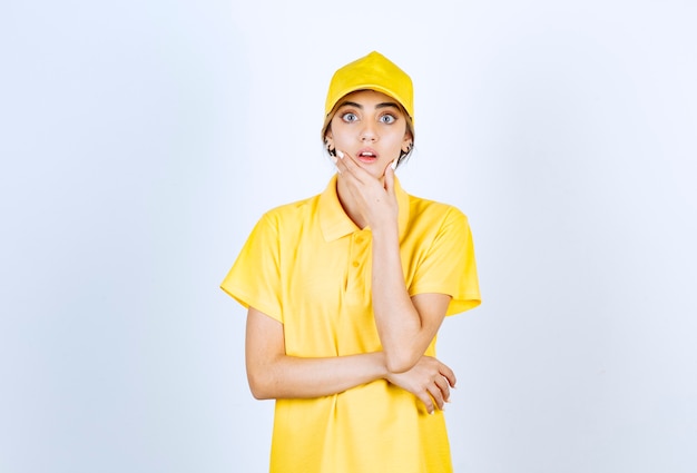 Delivery woman in yellow uniform standing and looking at camera.