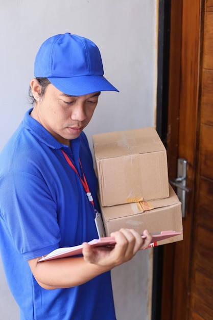 deliveryman holding pile of cardboard and checking document, sending package to customer.