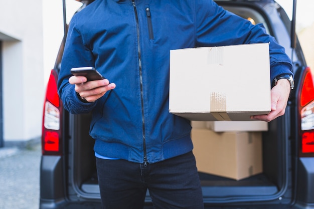 Deliveryman with box using phone