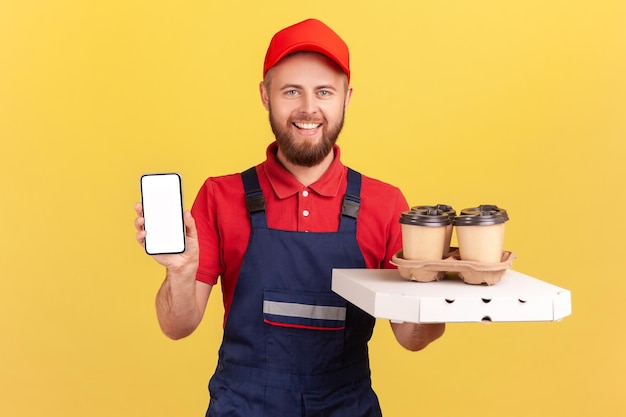 Deliveryman with pizza box and coffee in disposable cup and showing smart phone with empty display