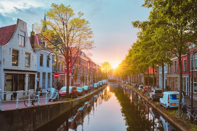 Delt canal with old houses and cars parked along on sunset