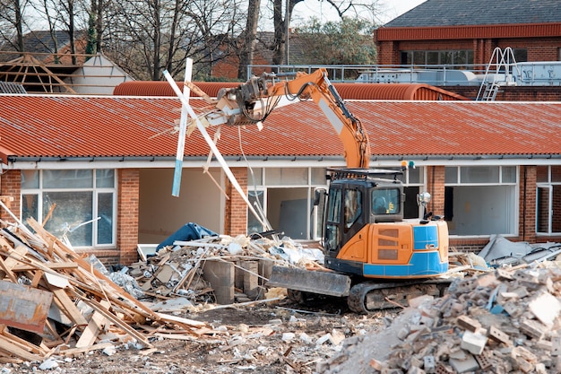 Demolition of old building with an excavator to give way for a new housing site and piles of rubble