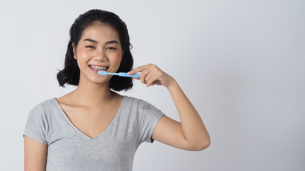 Dental brace teenager girl smile holding toothbrush . white teeth with blue braces. Dental care. Asian woman with contact lens and orthodontic accessories. Cosmetic dentistry.