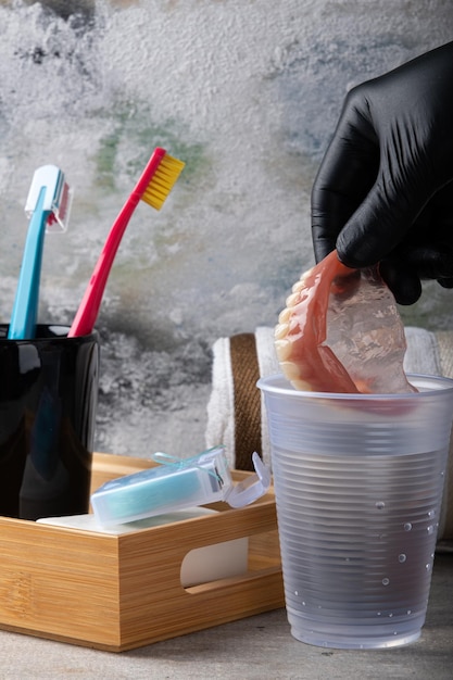 Dental care Putting complete denture into water cup Selective focus