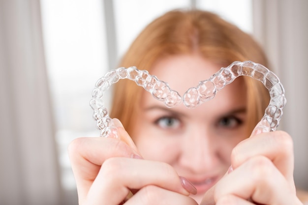 Dental careSmiling girl with red hair holding heart shaped aligners