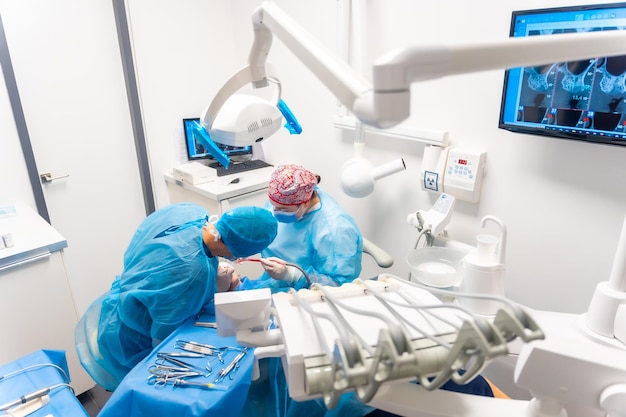 Dental clinic dentists in blue suits performing an operation on an implant