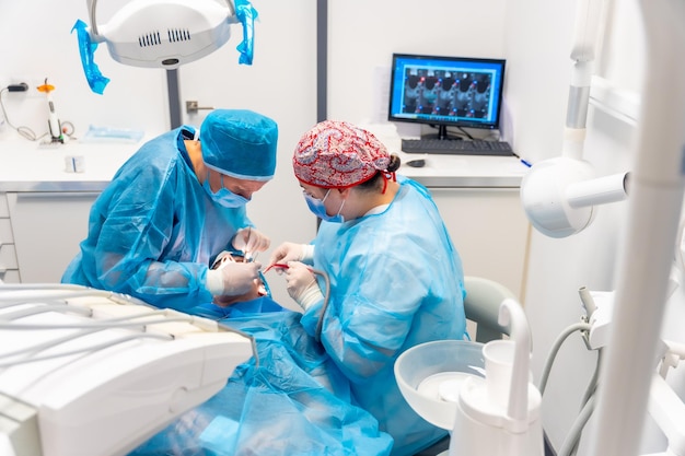 Dental clinic detail of dentists with blue suits performing an implant view from above of the operation