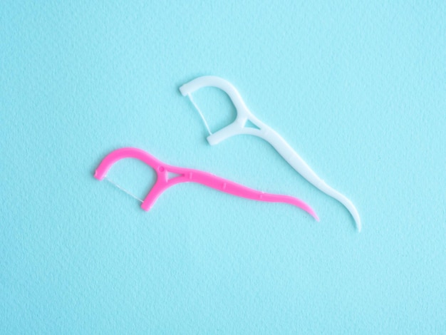 Dental floss with plastic toothpick white and pink on blue with space for text Dental concept