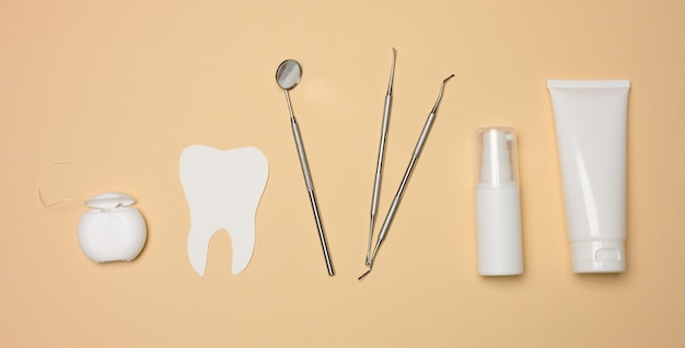 Dental mirror tube of toothpaste and dental floss on a brown background