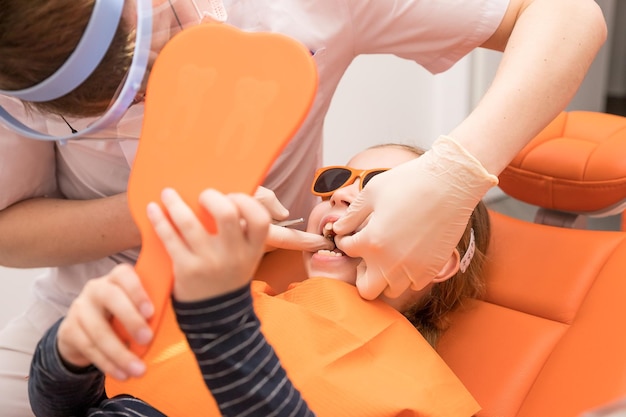 Dental plate Expansion of the jaw in a child teenage girl holding an orthodontic plate in her handsorthodontic doctor examine teeth and gums of little girl jawdental concept retainer for teeth