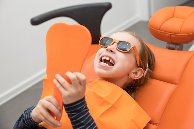 Dental plate Expansion of the jaw in a child teenage girl holding an orthodontic plate in her handsorthodontic doctor examine teeth and gums of little girl jawdental concept retainer for teeth