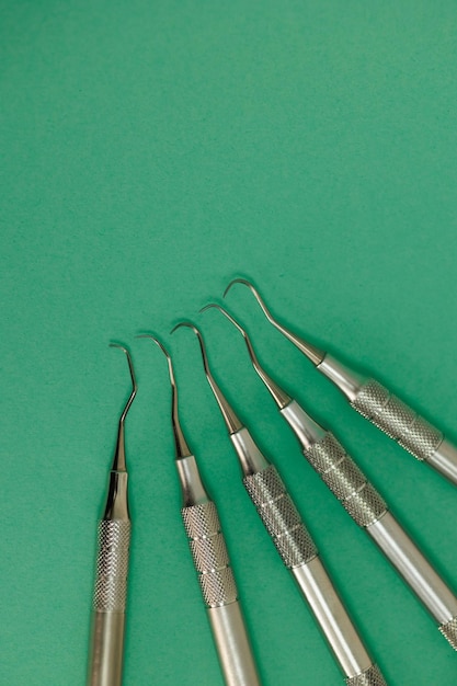 Dental scaler and probes on green background stainless medical instruments