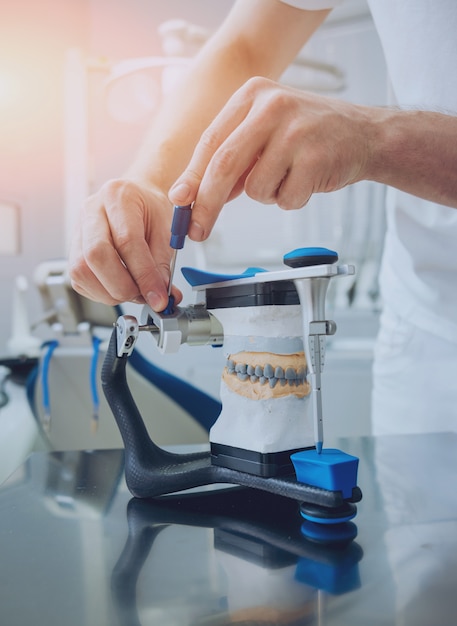 Dental technician working with articulator in dental lab