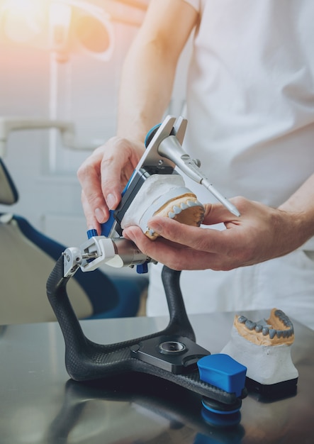 Dental technician working with articulator in dental lab