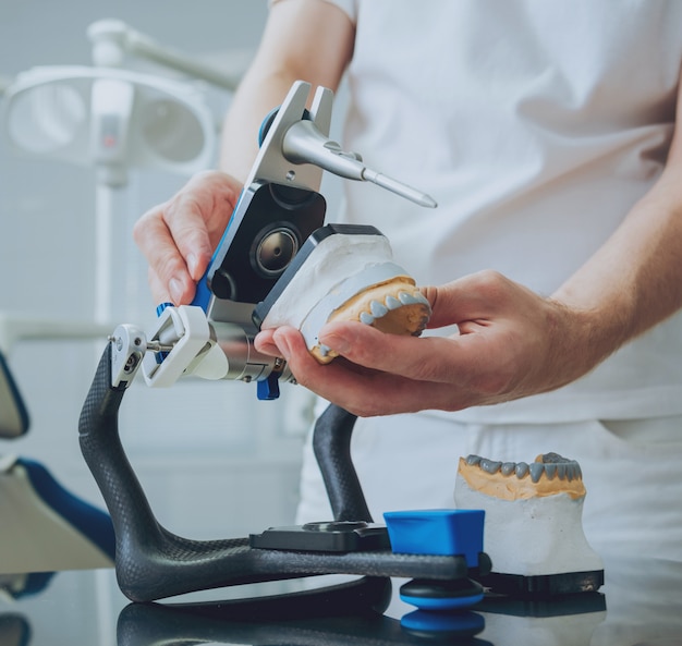 Dental technician working with articulator in dental lab