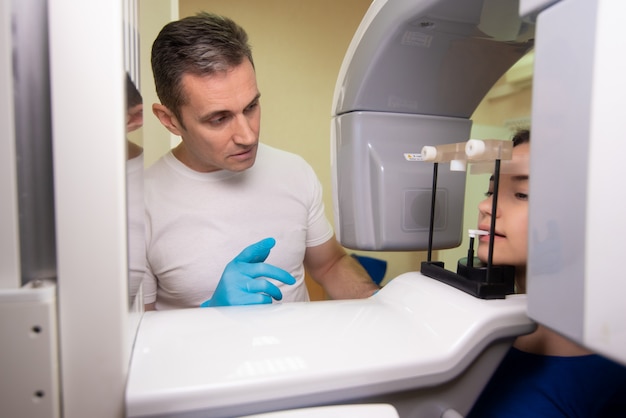 Dental tomography. Girl-patient stands in a tomograph, a doctor near the control panel