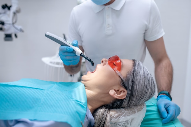 Dental treatment. Female patient in protective eyewear having a dental restoration at the dentists office