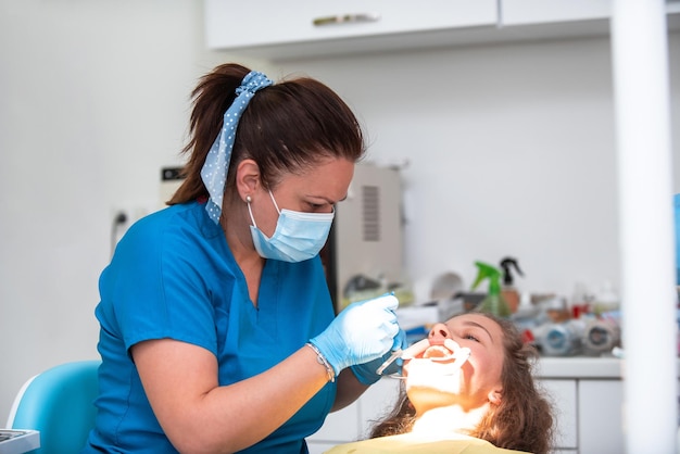 Dentist appointment at a dental clinic placing braces locks on the teeth and pulling the archwire to fix it