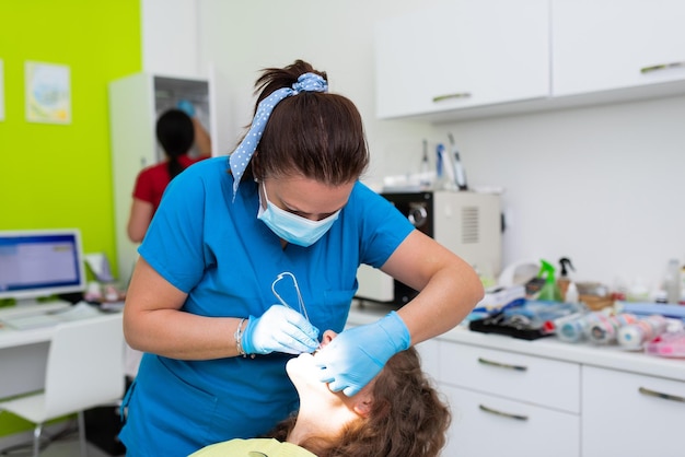 Dentist appointment at a dental clinic placing braces locks on the teeth and pulling the archwire to fix it