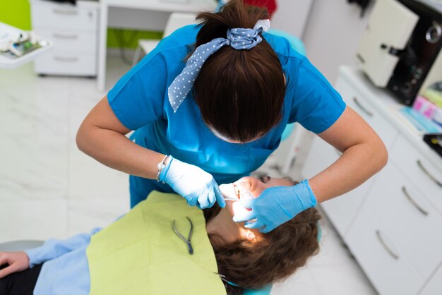 Dentist appointment at a dental clinic placing braces locks on the teeth and pulling the archwire to fix it