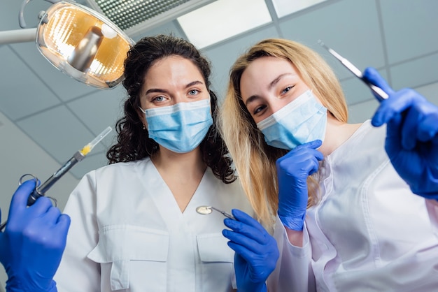 Dentist and assistant bent over the patient holding the instrument in their hands