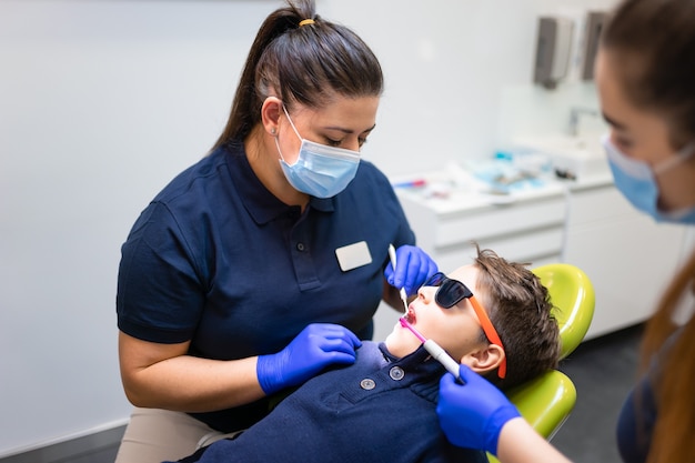 Dentist and assistant make preventive dental plaque cleaning for teenager