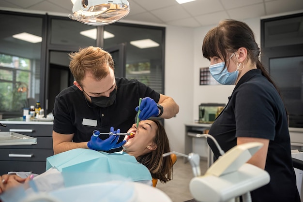 Dentist begins to check or examine the tooth of young girl patient lying on the dental chair