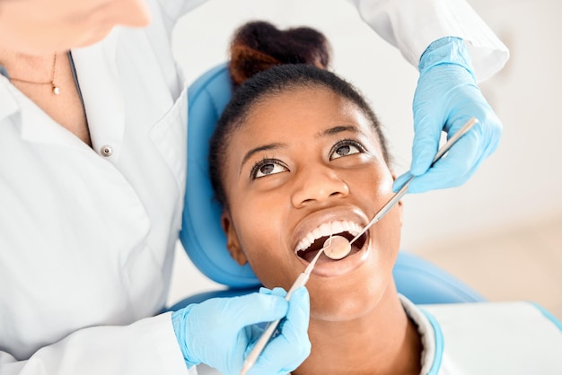 Dentist black woman and mouth cleaning of patient at a clinic with medical and healthcare for teeth Mirror orthodontist and African female person with wellness and dental work tool with care