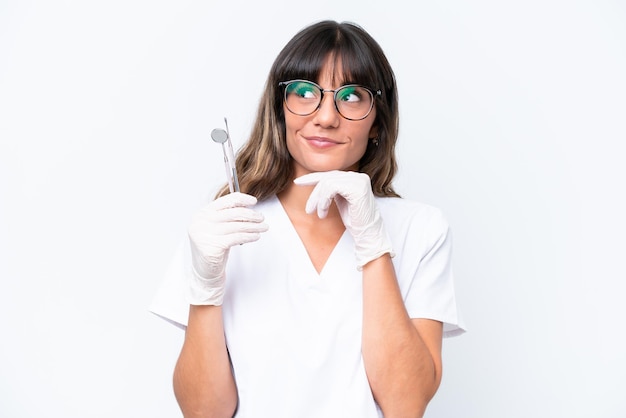 Dentist caucasian woman holding tools isolated on white background and looking up