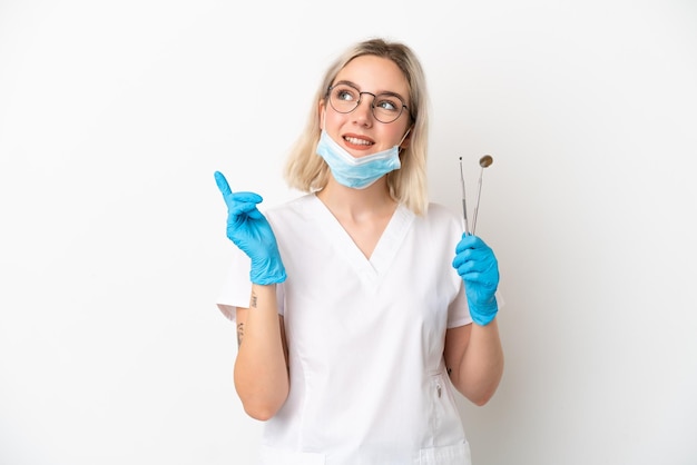 Dentist caucasian woman holding tools isolated on white background pointing up a great idea