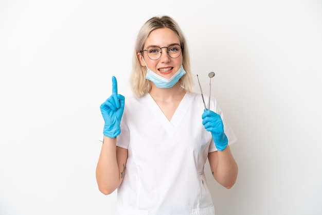 Dentist caucasian woman holding tools isolated on white background showing and lifting a finger in sign of the best