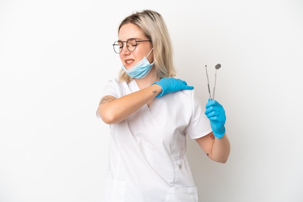 Dentist caucasian woman holding tools isolated on white background suffering from pain in shoulder for having made an effort