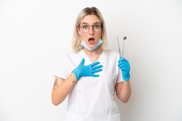 Dentist caucasian woman holding tools isolated on white background surprised and shocked while looking right