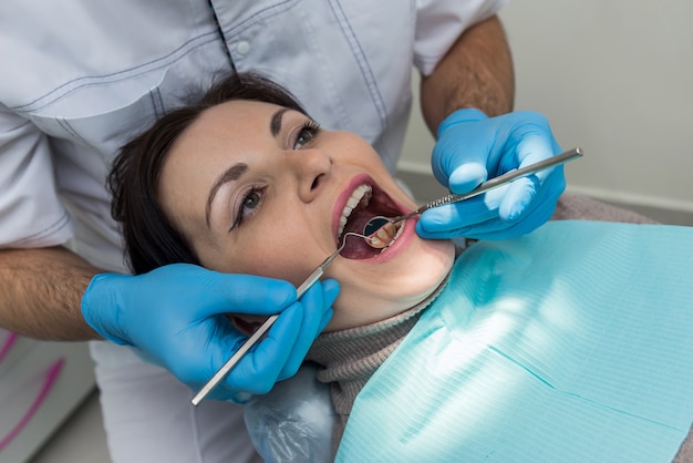 Dentist checking woman's teeth with mirror during visit