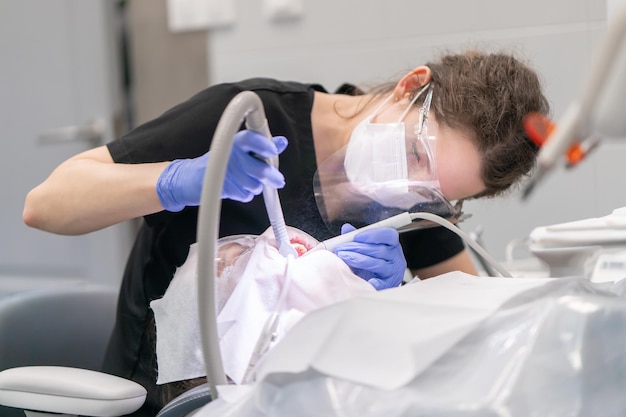 Photo a dentist cleans the teeth from plaque and tartar using an air abrasion device