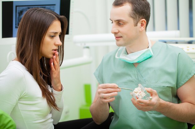 Dentist in dental office talking with female patient and preparing for treatment