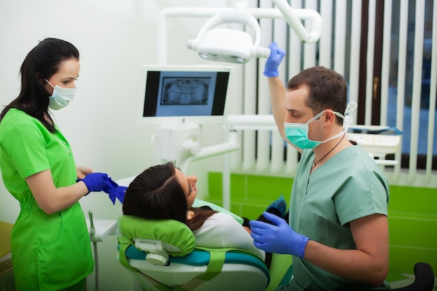 Dentist in dental office talking with female patient and preparing for treatment.