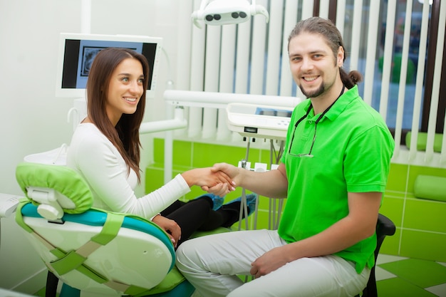 Dentist in dental office talking with female patient and preparing for treatment