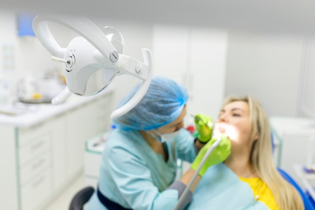 Dentist drills the lower tooth to the patient sitting in a chair