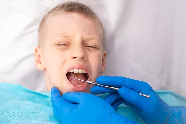 The dentist examines the child. Dentistry in children. The orthodontist examines the oral cavity of the kid. Sharp toothache. Caries on the teeth. Incorrect bite of teeth. High quality photo