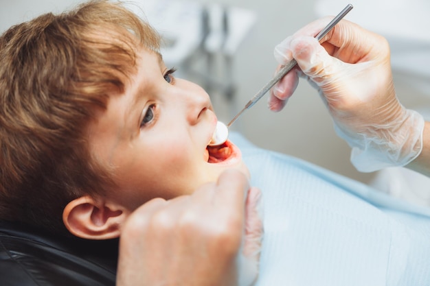 The dentist examines the teeth of a boy of 13 years old in the clinic pediatric dentistry